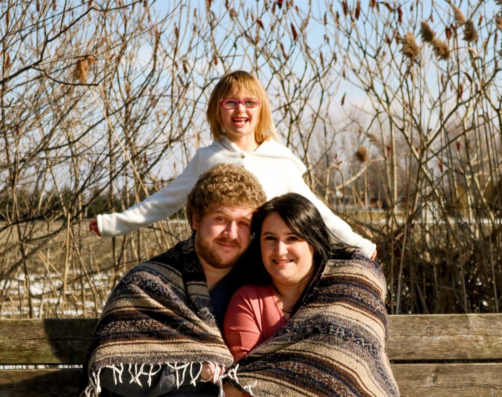 Bundled up — family wrapped in a blanket on a bench