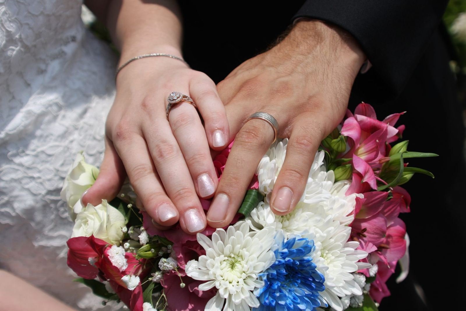 Bouquet and bands — hands with rings resting on a bouquet